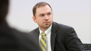 A man in a suit sits in court