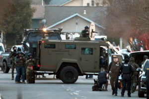 Law enforcement officers aim their weapons at a home during a standoff in Grants Pass