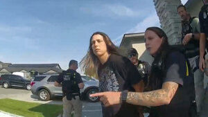 A still frame from bodyworn camera footage shows a woman being arrested outside a home.