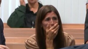 A woman sits with her hand over her face