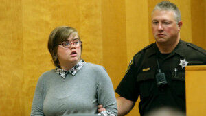 A woman is escorted by a deputy