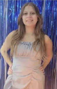 A girl stands in front of a blue background.