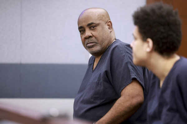 A man in a prison jumpsuit listens in court.