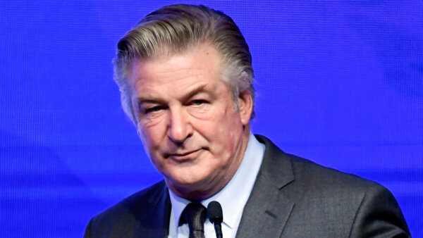 Alec Baldwin stands before a microphone