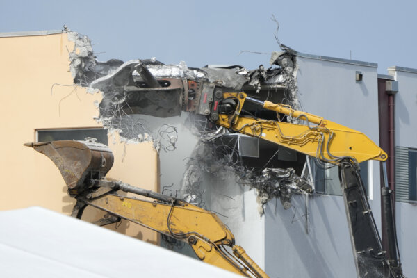 excavator removes a piece of a building