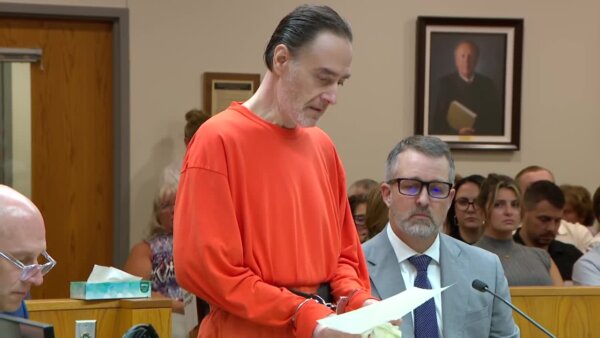 Nicolae Miu stands in shackles while he addresses the court