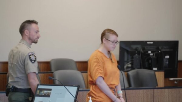 woman stands in court with attorney
