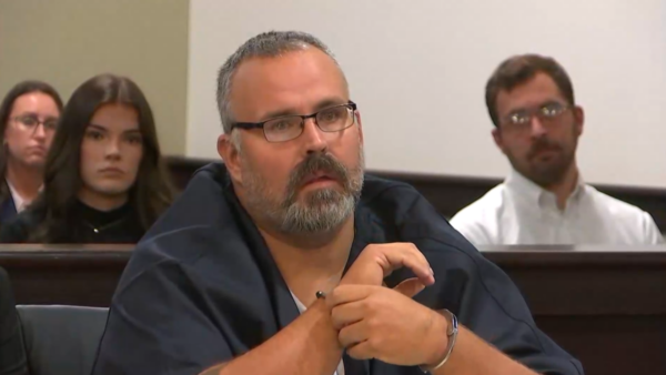 A man sits in court wearing handcuffs