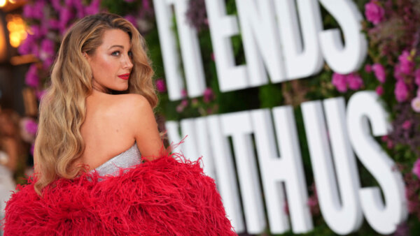 Blake Lively poses for a photo in front of a backdrop saying 'It Ends With Us'