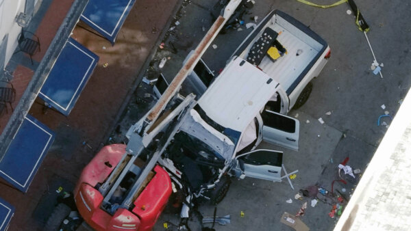 A black flag with white lettering lies on the ground rolled up behind a pickup truck that a man drove into a crowd on Bourbon Street