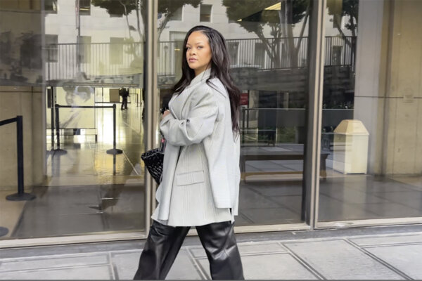 Pretty woman stares down the camera. She has silky long hair and shiny leather pants.