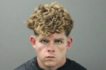 mugshot of a young, blonde, curly-haired man