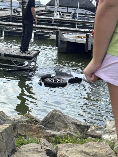 People stand over the site where investigators say 40-year-old Ruth Miller of Millersburg, Ohio, drove a golf cart into Atwood Lake