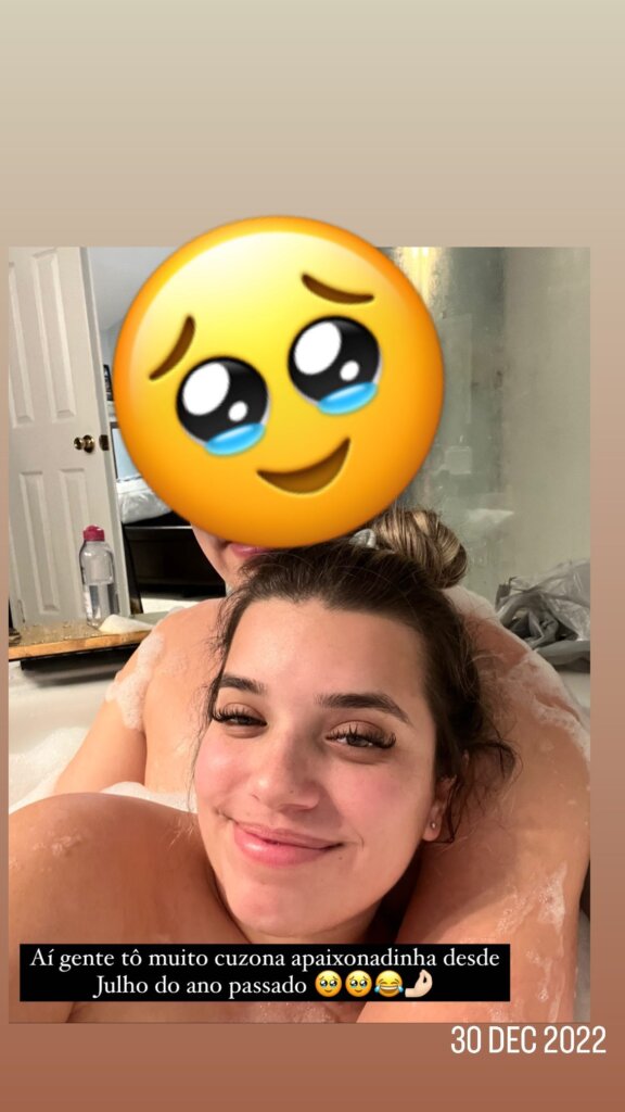 Selfie of woman and man in a bathtub with an emoji over the face of the man