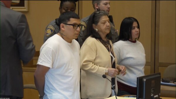 Defendants stand next to interpreter in court